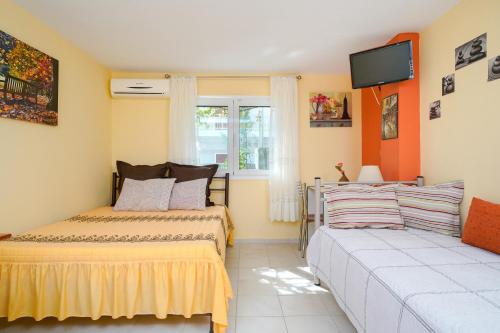 a bedroom with two beds and a tv on the wall at Thomas Apartments in Skala Marion