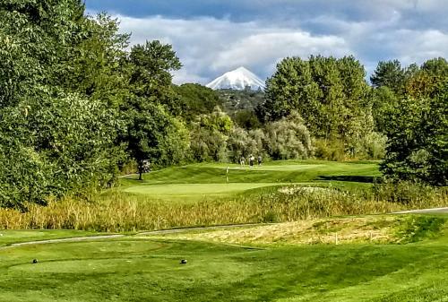 a golf course with a snow covered mountain in the background at Resort at Eagle Point Golf Club Lodging in Medford