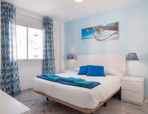 a bedroom with a bed with blue pillows on it at Happy Nest in Benalmádena