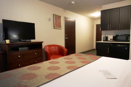 a hotel room with a bed and a flat screen tv at Ramada by Wyndham Moose Jaw in Moose Jaw