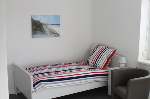 Cama en habitación blanca con silla en 3 Zimmer Ferienwohnung - Woltorf, en Peine