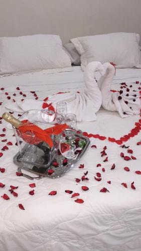 a bed with red roses on it with a bottle of wine and aeder at Sol de Luque Casa-hotel in Luque