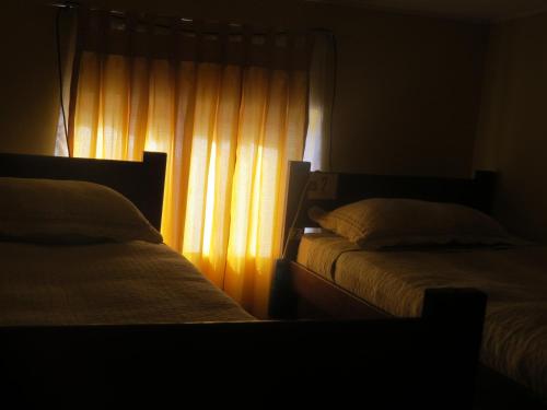 a bedroom with two beds and a window with curtains at Hostal Alabalti in San Pedro de Atacama