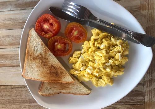 een bord met roerei, toast en tomaten bij Daphila Cottage in Nusa Penida