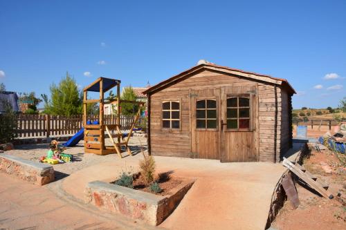 a small wooden shed with a playground and a slide at El Retiro de Cervantes in Ossa de Montiel