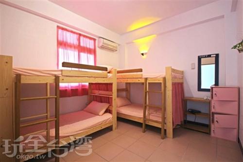 a room with three bunk beds in a room at 七十腳落背包客棧 in Green Island