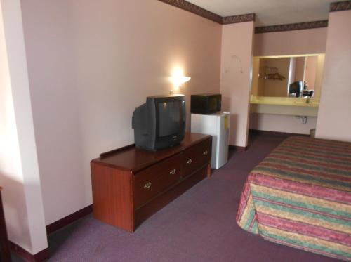 a hotel room with a bed and a tv on a dresser at Executive Inn & Suites - Covington in Covington