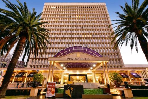 a hotel with palm trees in front of a building at Duxton Hotel Perth in Perth