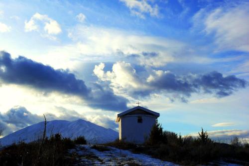 a small white chapel on a hill with a cloudy sky at Petrini Gonia in Livadero