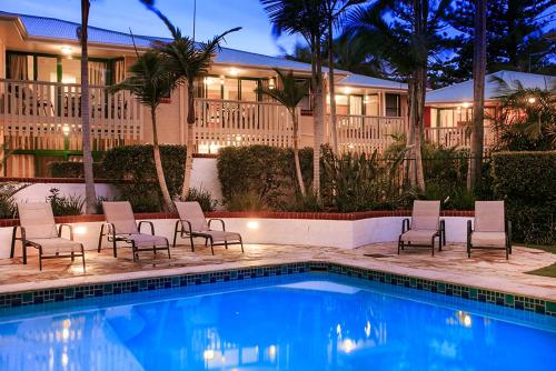 a resort with a pool with chairs and a building at The Crest Byron Bay in Byron Bay