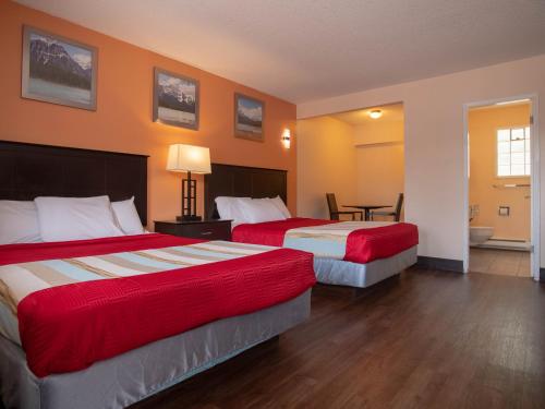 a hotel room with two beds and a table at Best Budget Inn & Suites Kamloops in Kamloops