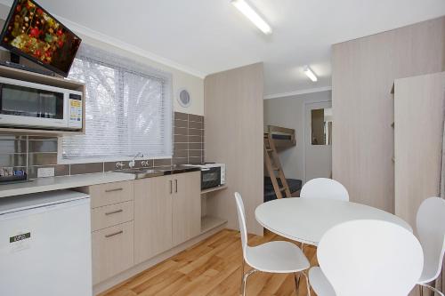 a kitchen with a table and chairs and a refrigerator at Warrnambool Motel and Holiday Park in Warrnambool