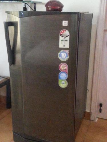 a black refrigerator with many magnets on it at BEAUTIFUL SPACIOUS STUDIO APT IN CANDOLIM with Wifi in Candolim