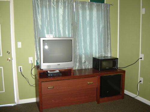 uma televisão numa cómoda de madeira com um micro-ondas em Bali Hai Motel em Yakima