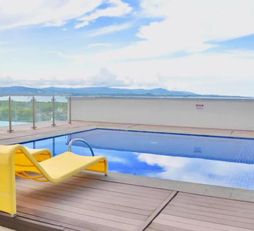 a yellow chair sitting next to a swimming pool at Mactan Newtown Cebu Affordable Suite! in Mactan