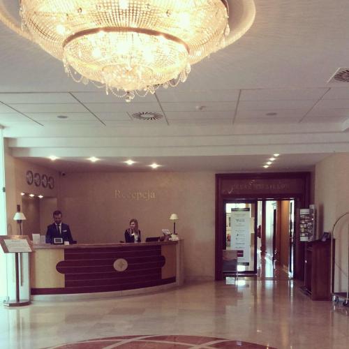 two people sitting at a reception desk in a lobby at GRAND HOTEL Kielce in Kielce