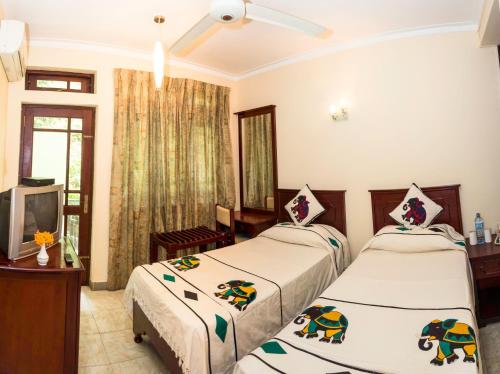 a bedroom with two beds and a tv in it at Amanda Hills in Kandy