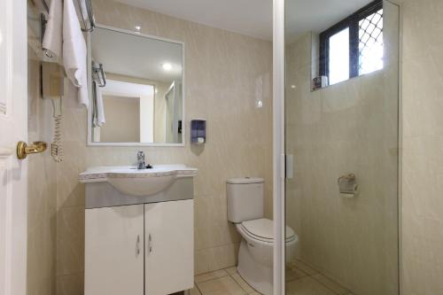 a bathroom with a toilet and a sink and a mirror at Novena Palms Motel in Brisbane