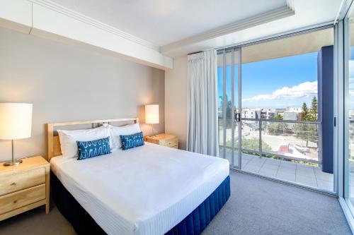 a bedroom with a bed and a large window at Pumicestone Blue in Caloundra