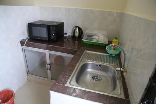 Una pequeña cocina con fregadero y microondas. en Panhanita Apartment and Villa, en Siem Reap