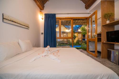 a bedroom with a large white bed and a tv at La Belle Anbang Homestay in Hoi An