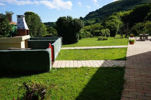 a view of a grassy yard with a brick walkway at Casas Das Flores in Lajes das Flores