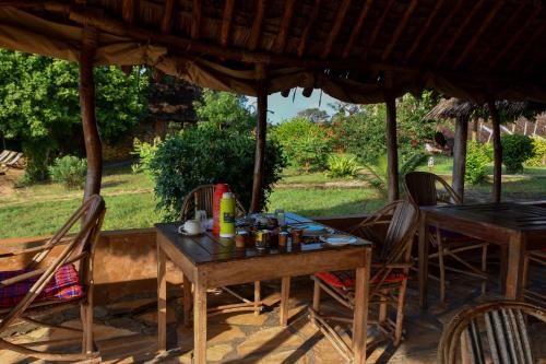 a wooden table and chairs under an umbrella at Bahari Pori Resort in Pangani