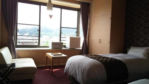 ein Hotelzimmer mit einem Bett, einem Stuhl und einem Fenster in der Unterkunft Sunrise Katsuura in Nachikatsuura