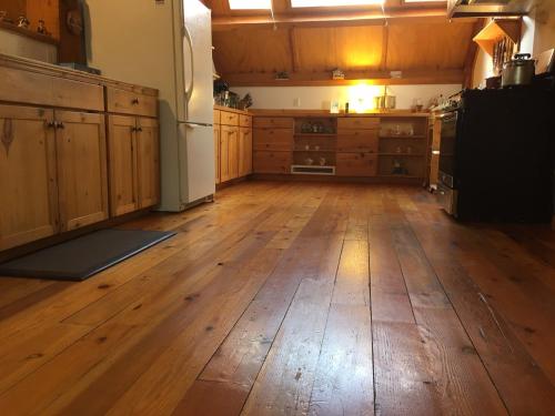 an empty kitchen with wooden floors and a refrigerator at Owl Street Lodge in Hope