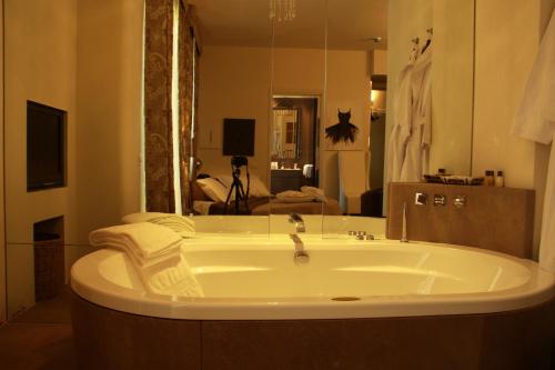 a large bath tub in a bathroom with a living room at Balneum Boutique Hotel & B&B in Bagno di Romagna