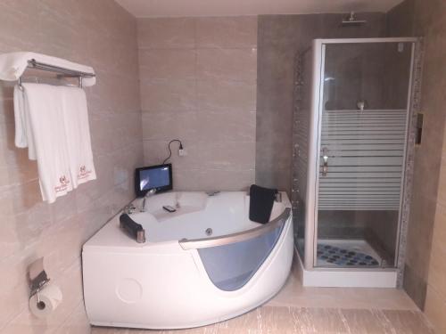 a bathroom with a white tub and a shower at Tiffany Diamond Hotels LTD - Makunganya in Dar es Salaam