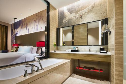 a bathroom with a bed and a bath tub and a sink at Wanda Realm Qiqihar in Qiqihar