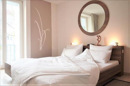 a bedroom with a large white bed with a mirror at Strandappartement in Binz in Binz