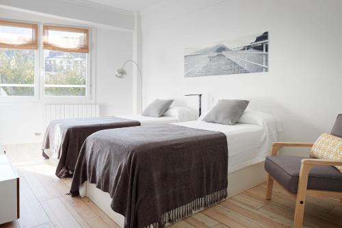 1 dormitorio con 2 camas y 1 silla en Soroa Apartment, en San Sebastián