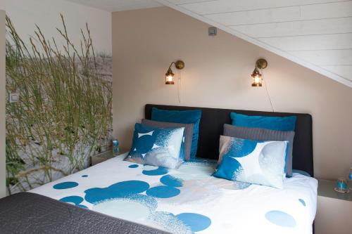 um quarto com uma cama com almofadas azuis e brancas em B&B Bij MoeMee em Gent