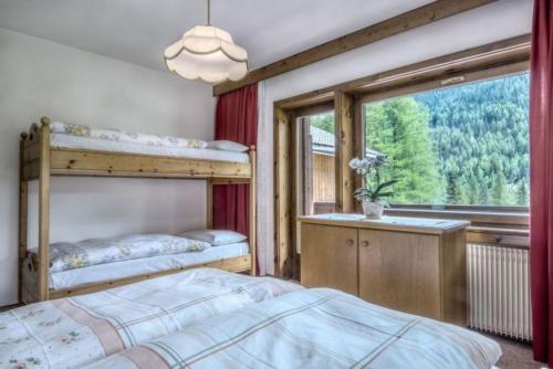 una camera con 2 letti a castello e una finestra di Apartments Fiordalisi a Colfosco