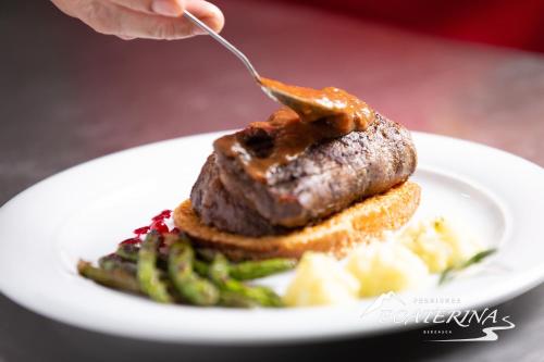 a plate of food with a piece of meat and asparagus at Pensiunea Ecaterina in Berzasca