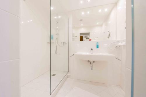 a white bathroom with a sink and a shower at Hotel Bellevue in Seeboden
