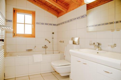 a bathroom with a toilet and a tub and a sink at Apartment Bärhag - GRIWA RENT AG in Grindelwald