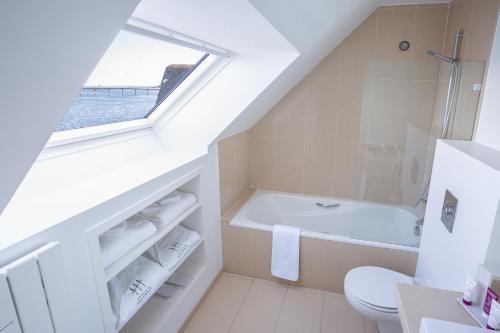 a bathroom with a toilet, tub, sink and window at Hotel Le Temps De Vivre in Roscoff