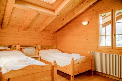 グリンデルワルトにあるApartment Chamonix - GRIWA RENT AGの木造家屋内のベッドルーム(ベッド2台付)