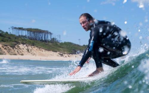 a man riding a wave on a surfboard in the ocean at Somo Garden Villas in Somo