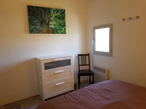 - une chambre avec un lit et une commode avec une photo sur le mur dans l'établissement les marines de Tamaris, à La Seyne-sur-Mer