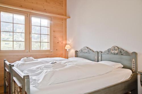 - une chambre avec 2 lits avec des draps blancs et une fenêtre dans l'établissement Apartment Eiger - GRIWA RENT AG, à Grindelwald