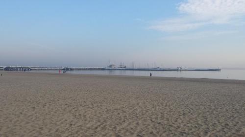 a sandy beach with a pier in the water at Pensjonat Eden in Sopot