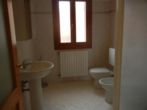 een badkamer met een wastafel, een toilet en een raam bij CASA VACANZE MEDICINA in Medicina