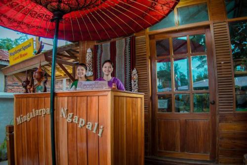 Mingalarpar Ngapali Guest House في نغابالي: امرأتين واقفتين عند بار فيه مظله