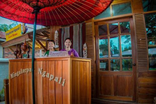 two women are standing at a bar with an umbrella at Mingalarpar Ngapali Guest House in Ngapali