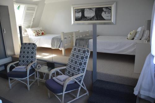 a bedroom with two beds and two chairs and a lamp at Vergenoegd Guesthouse in Panorama