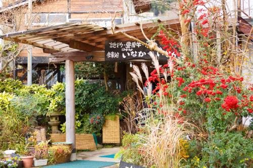 a garden with a wooden pergola and flowers at Yufuin Inakamura Inakaso in Yufuin